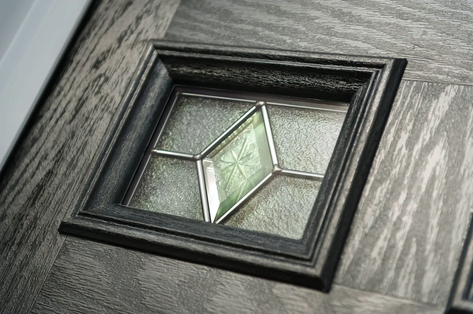 Close-up of bevelled decorative glass in a dark woodgrain composite door