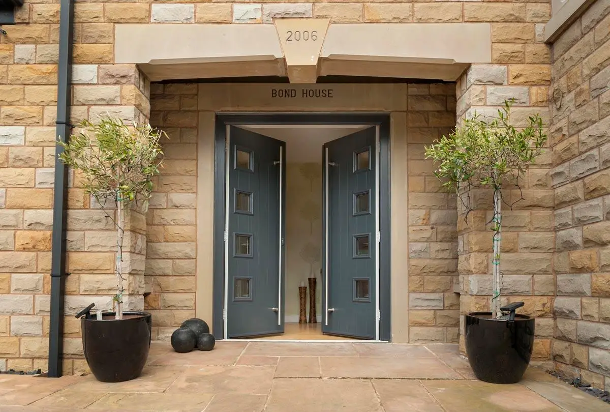 Grey contemporary double doors with square glass lights in a stone porch