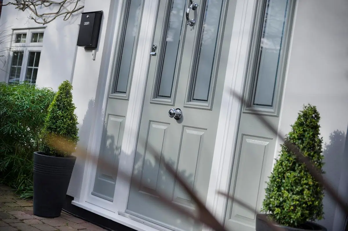 Light grey composite door with glazed side panels on a white rendered house