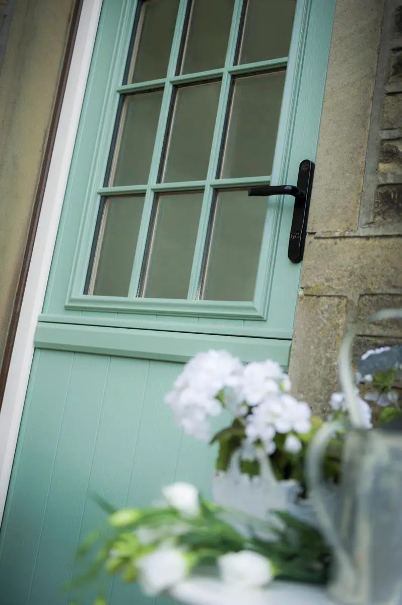 Pale green composite door with Georgian-style glazing and a black lever handle