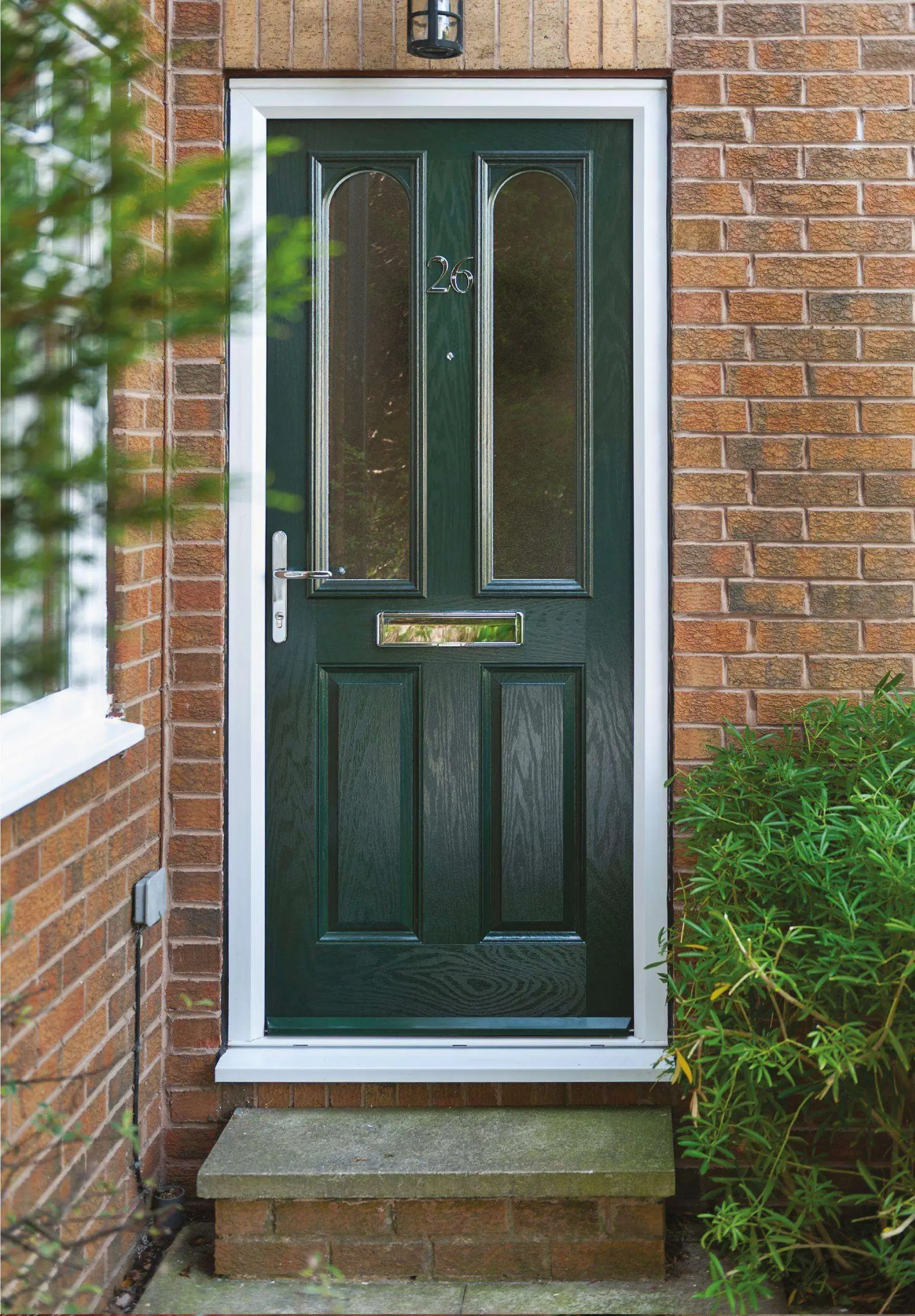 Dark green composite door with twin glazed panels in a red-brick house
