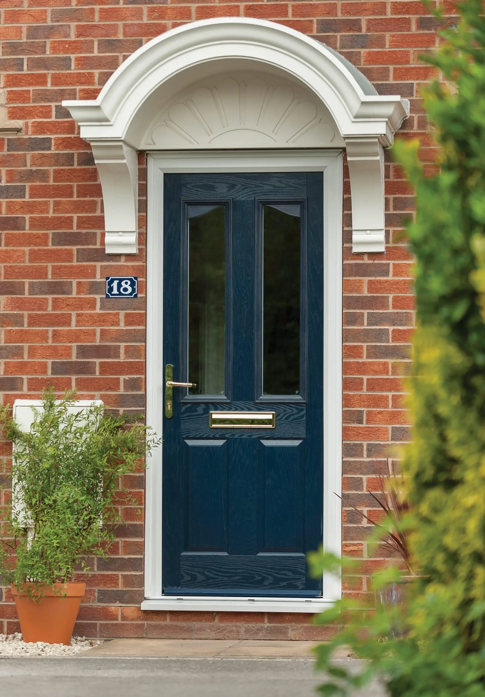 Navy composite door with glazed top panels beneath a white arched canopy