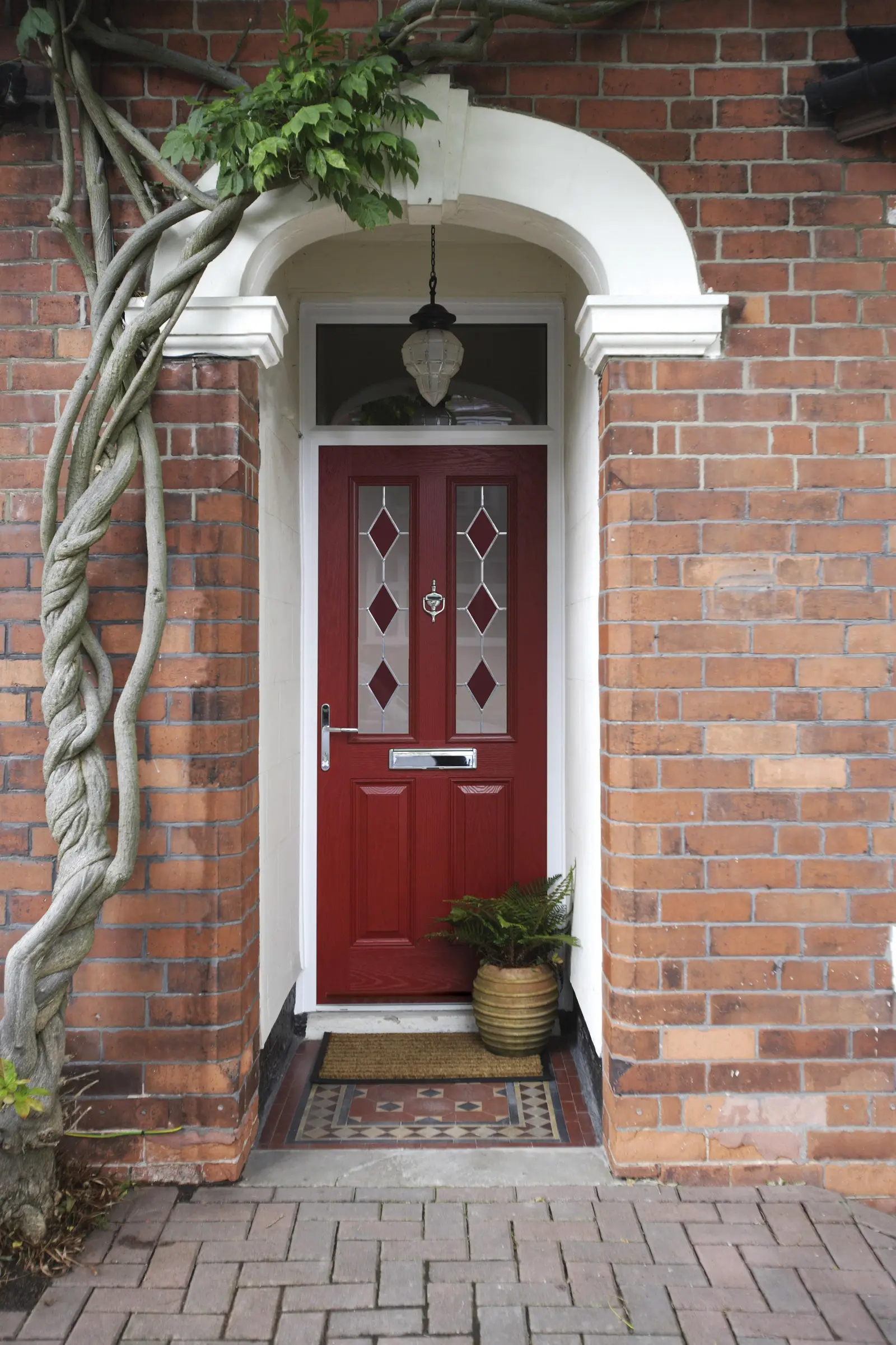 Red composite door with diamond glazed panels under an arched brick porch