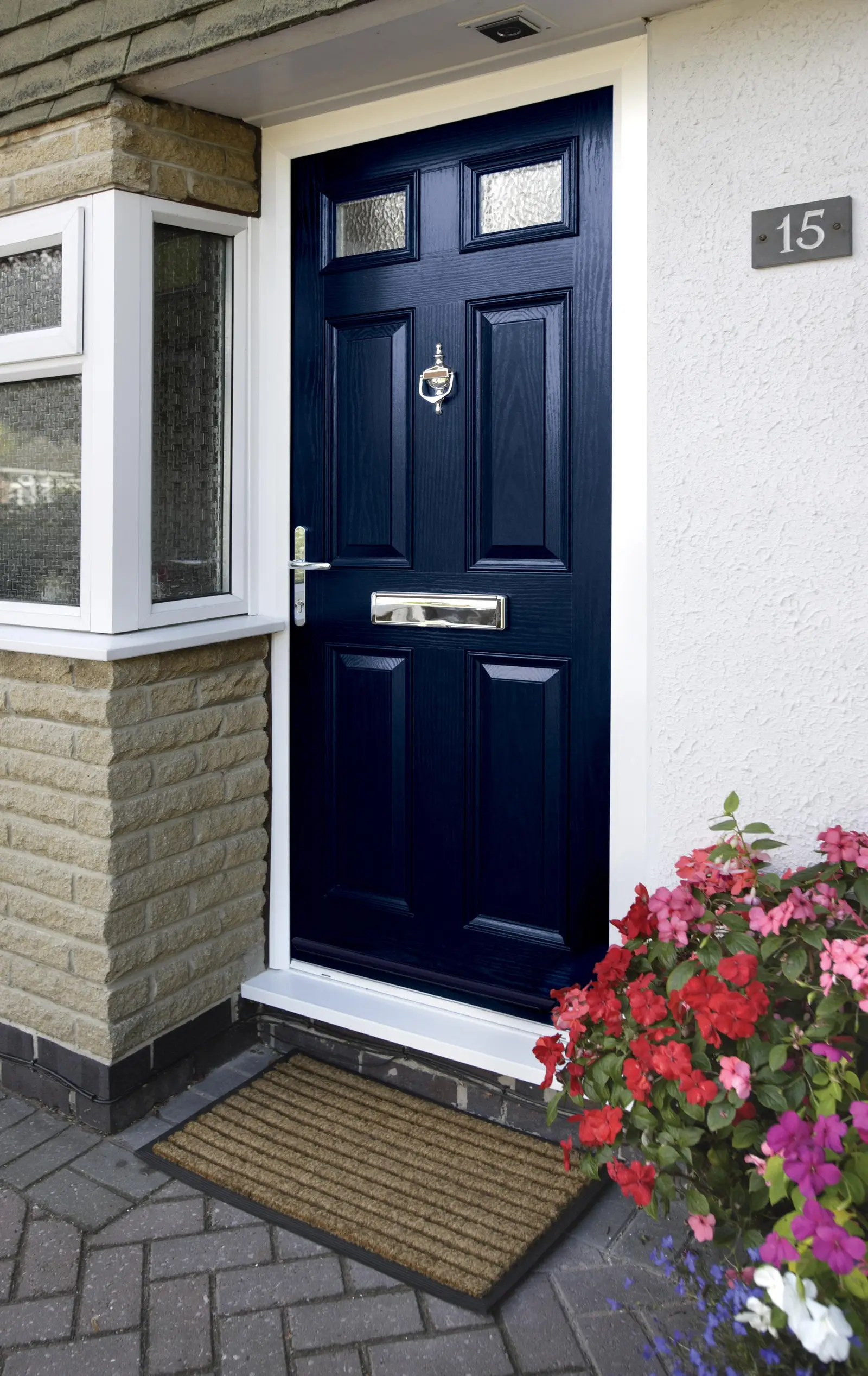 Navy blue composite door with chrome furniture and flowering planters