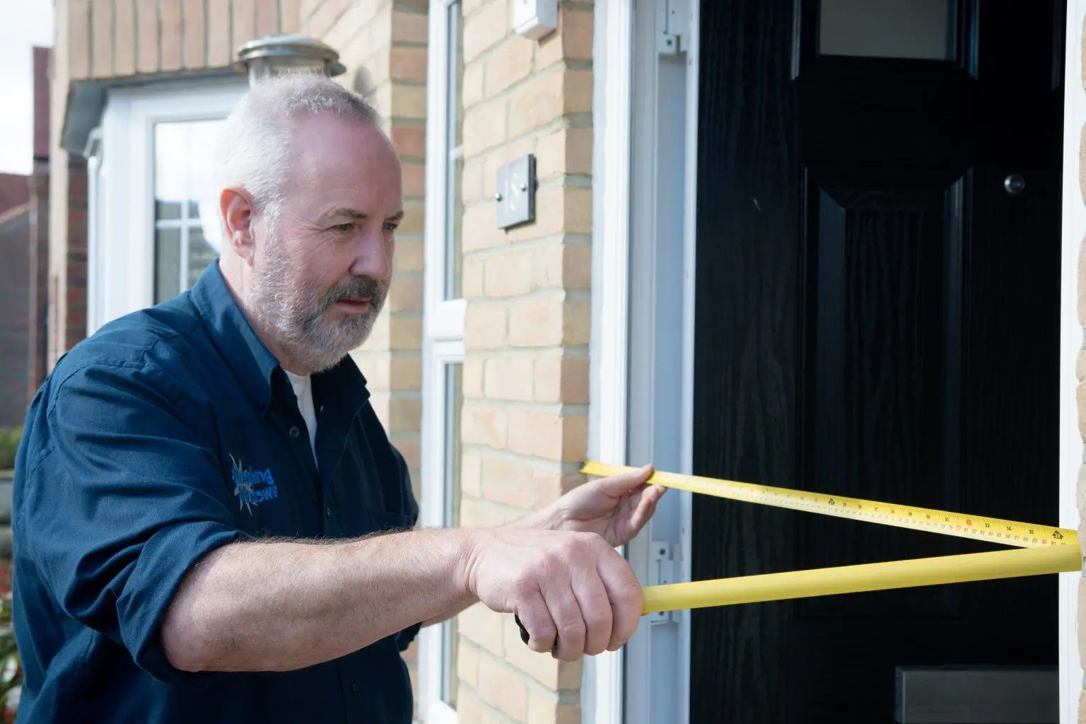 A Smashing Windows fitter measuring a door opening with a tape measure